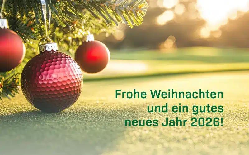 drei Weihnachtskugeln h&auml;ngen an einem Tannenzweig auf einen Golfplatz